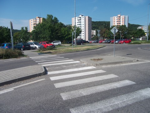 Priechod pre chodcov v Dúbravke. Stredovým ostrovčekom sa prechádza bez zapustených obrubníkov, či akýchkoľvek iných nerovností. Ide o súvislý asfaltový povrch. Podobne by mali byť riešené všetky križovania cestičiek pre cyklistov s vozovkou.